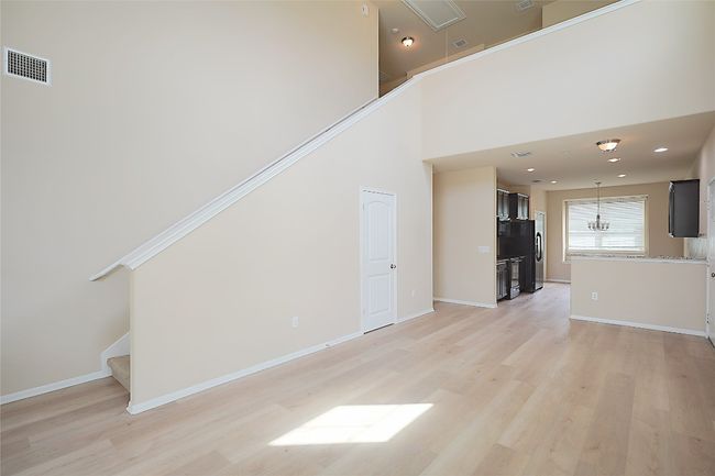 Unfurnished living room featuring light wood-style floors, stairs, a chandelier, recessed lighting, and a towering ceiling | Image 4