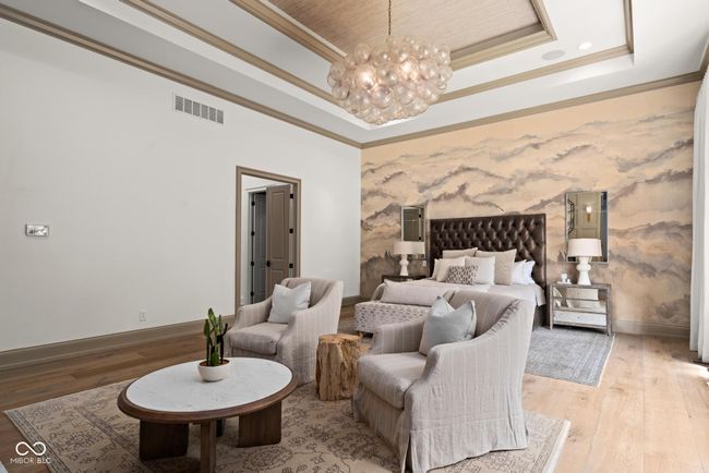 primary bedroom with a raised ceiling, ornamental molding, baseboards, a chandelier, and light wood finished floors | Image 22