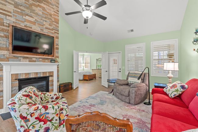 Living room featuring vaulted ceiling, visible vents, a ceiling fan, a fireplace, and wood finished floors | Image 14