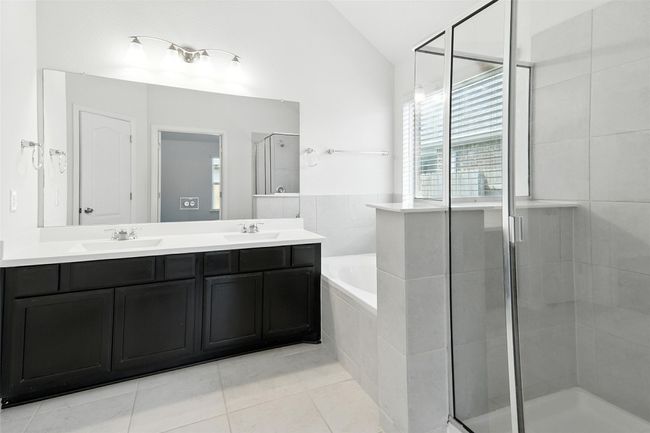 Bathroom featuring double vanity, vaulted ceiling, a stall shower, tile patterned floors, and a garden tub | Image 29