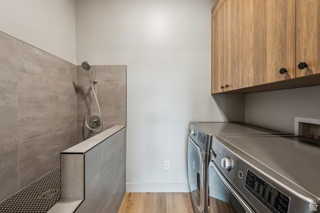 Laundry room featuring washing machine and dryer, baseboards, light wood-style floors, and cabinet space | Image 42