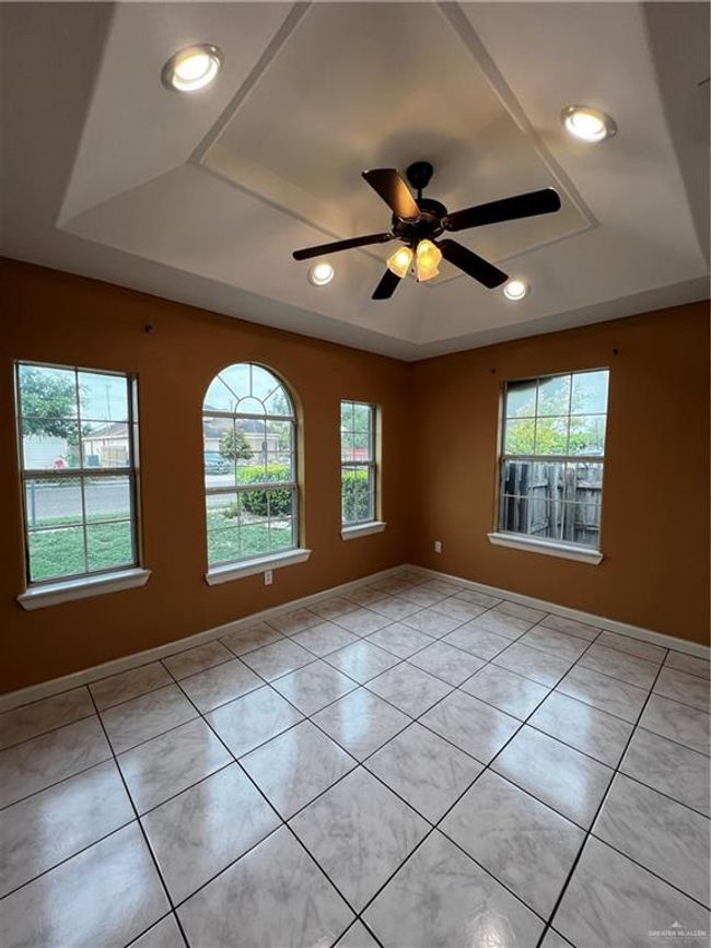 Empty room featuring light tile patterned flooring, a ceiling fan, recessed lighting, a tray ceiling, and baseboards | Image 6
