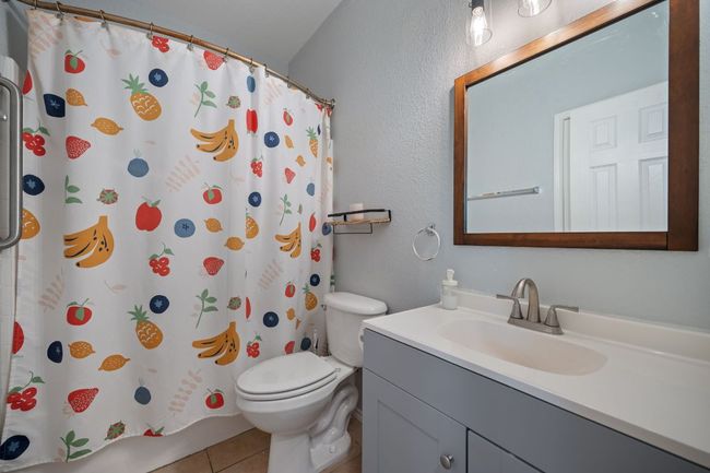 Bathroom featuring vanity, tile patterned flooring, toilet, a shower with curtain, and a textured wall | Image 21