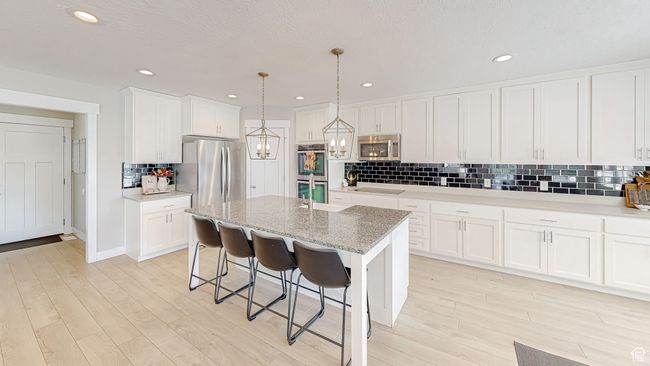 Kitchen with white cabinetry, stainless steel appliances, an inviting chandelier, and light wood-type flooring | Image 5