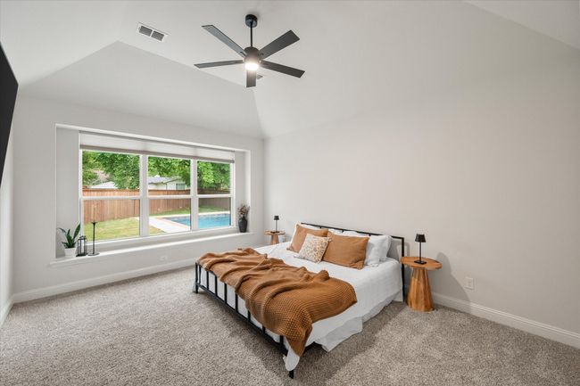 First floor primary suite features elegant vaulted ceilings and a modern lit ceiling fan. | Image 21
