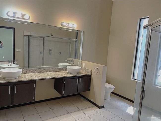 Full bathroom with double vanity, a stall shower, toilet, and tile patterned flooring | Image 16