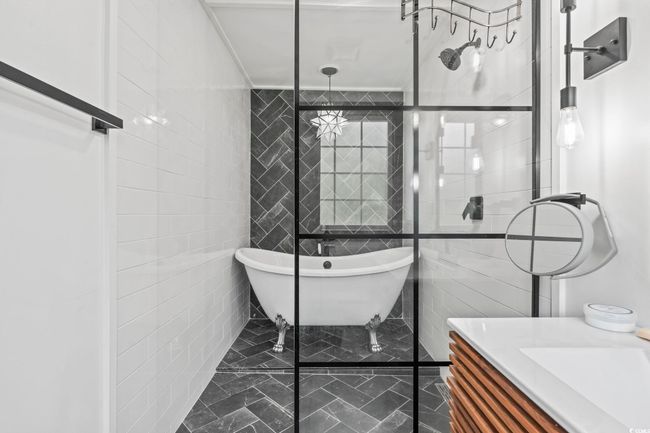 Bathroom featuring marble look tiles, tile walls, a freestanding tub, and vanity | Image 31