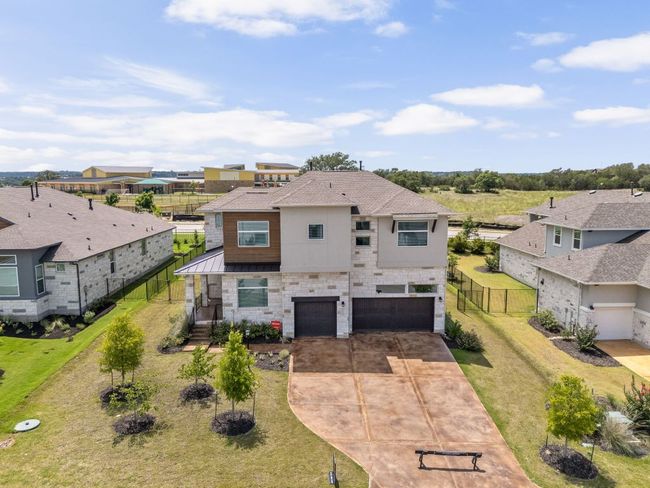 View of front of house featuring a garage, concrete driveway, a standing seam roof, a residential view, and metal roof | Image 34