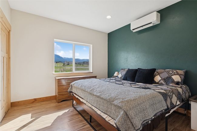 Bedroom with a wall mounted AC, wood finished floors, baseboards, and recessed lighting | Image 13