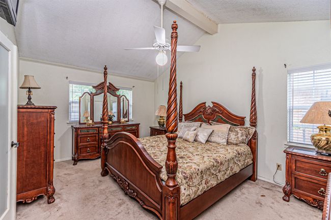 Bedroom with a textured ceiling, lofted ceiling with beams, a ceiling fan, and light carpet | Image 14