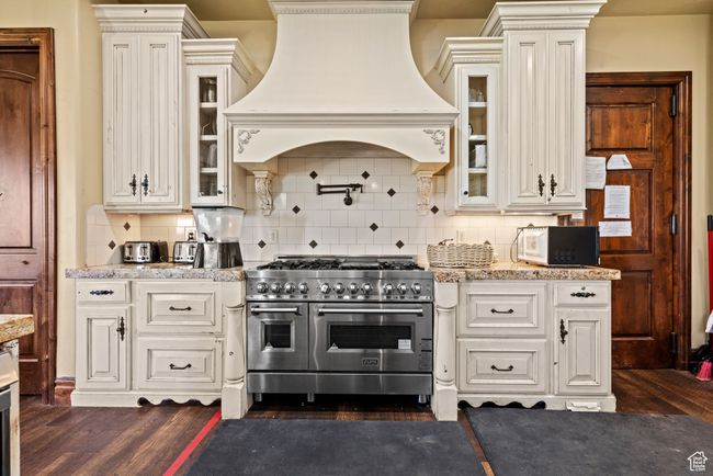 Kitchen featuring custom range hood, white microwave, dark wood-style flooring, and range with two ovens | Image 24
