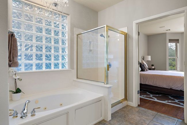 The primary bathroom offers dual vanities, a large soaking tub, a walk-in shower, and a large, walk-in closet. | Image 12