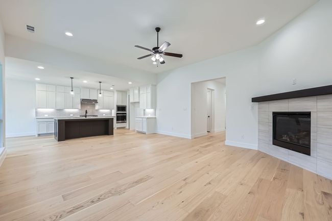 Unfurnished living room featuring visible vents, recessed lighting, ceiling fan, light wood finished floors, and a tiled fireplace | Image 5