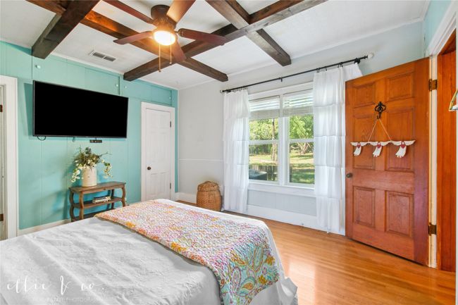 Bedroom with light wood-style floors, coffered ceiling, beamed ceiling, and a ceiling fan | Image 19