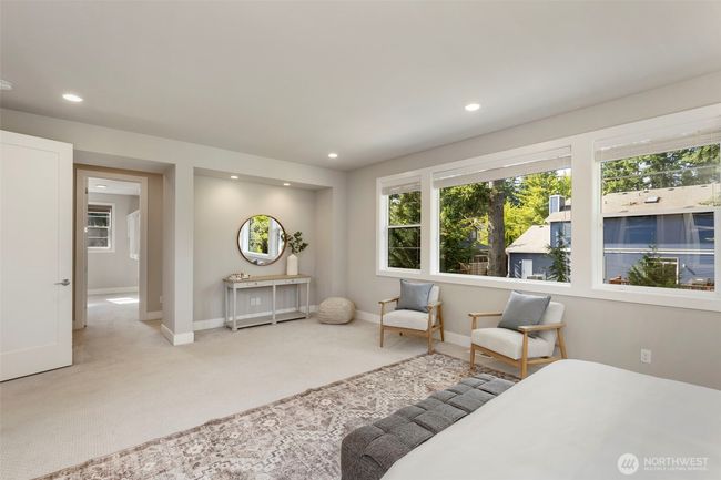 From this angle, the expansive primary suite reveals a cozy reading nook and a sunlit path leading to the luxurious en suite bath and walk-in closet. Clean lines, recessed lighting, and oversized windows create a tranquil, elevated space designed for everyday indulgence. | Image 28