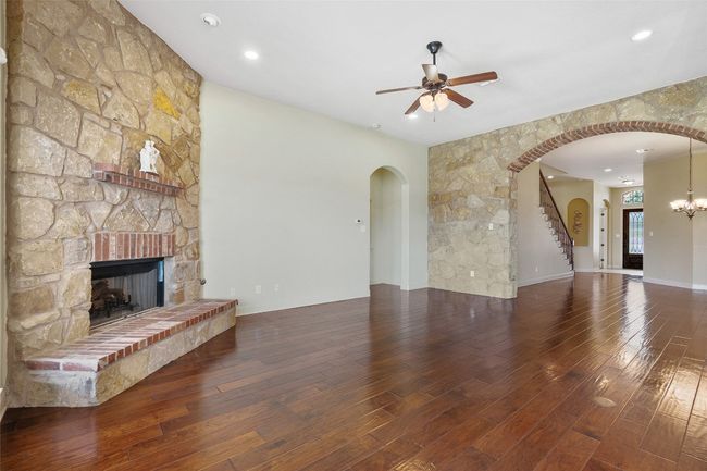 Unfurnished living room featuring hardwood / wood-style flooring, arched walkways, ceiling fan, a fireplace, and recessed lighting | Image 16