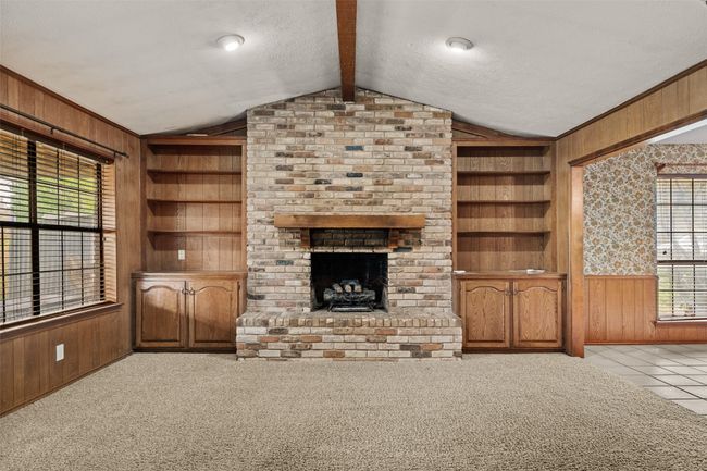 Unfurnished living room featuring built in features and wood walls | Image 6