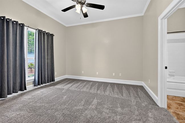 Carpeted empty room featuring ornamental molding, ceiling fan, and baseboards | Image 23