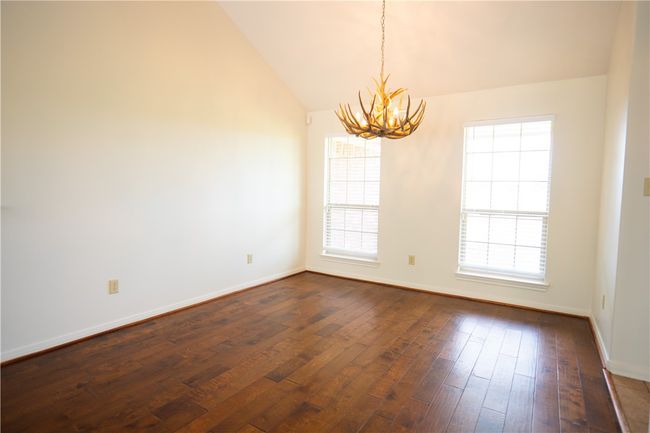 Spare room with a chandelier, plenty of natural light, dark wood finished floors, and lofted ceiling | Image 18