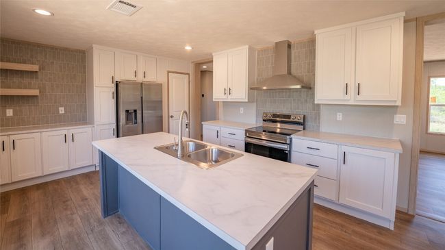 Kitchen with stainless steel appliances, wall chimney range hood, tasteful backsplash, recessed lighting, and white cabinetry | Image 23