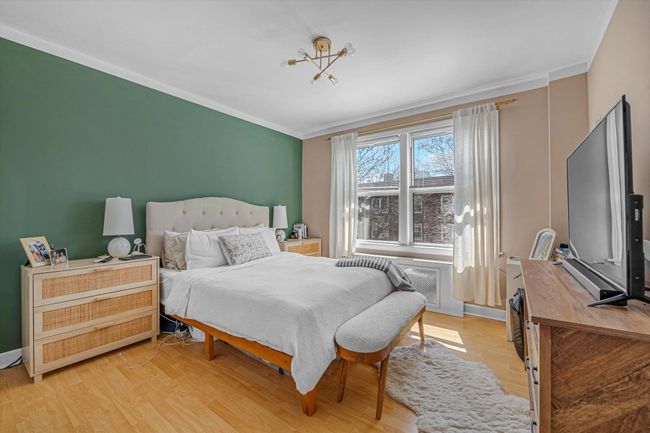 Bedroom with light wood-style floors, crown molding, baseboards, and an inviting chandelier | Image 7