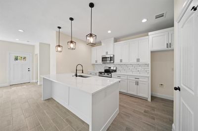 Kitchen featuring backsplash, sink, stainless steel appliances, and white cabinetry | Image 3