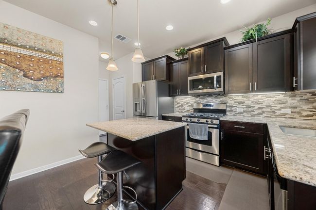 The island kitchen boasts desirable modern finished including granite countertops and gorgeous contemporary cabinetry with modern pulls. | Image 14