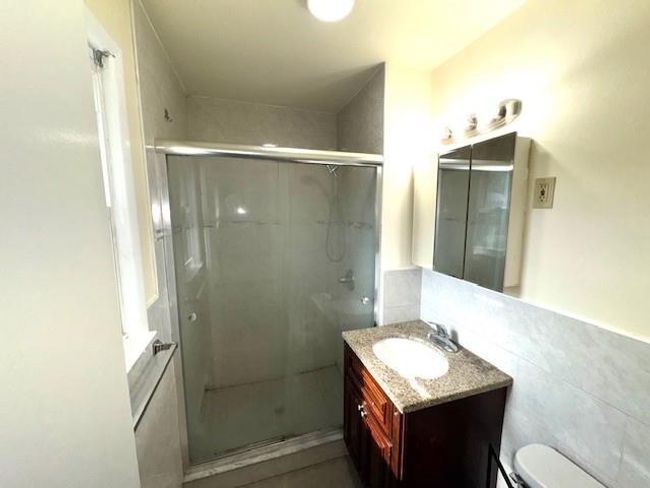 Bathroom featuring vanity, a stall shower, toilet, and tile walls | Image 8