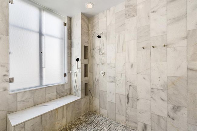 Marble bench seating offset by basketweave tile flooring. Dornbracht designer white matte fixtures. | Image 23