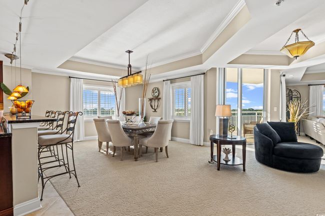 Carpeted dining room featuring a tray ceiling, plenty of natural light, and ornamental molding | Image 12