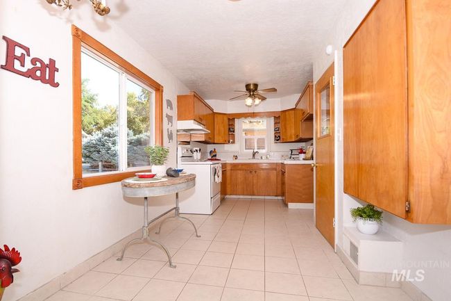 Kitchen featuring electric range, light countertops, under cabinet range hood, a ceiling fan, and brown cabinetry | Image 10