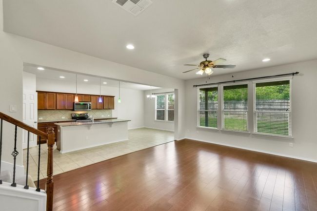 Unfurnished living room featuring recessed lighting, visible vents, baseboards, and ceiling fan with notable chandelier | Image 6