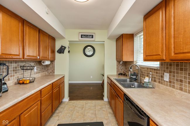 kitchen with black dishwasher, brown cabinets, light countertops, and tasteful backsplash | Image 8