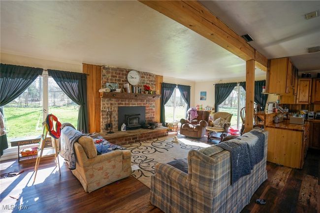Living room featuring visible vents, wood finished floors, and a wood stove | Image 9
