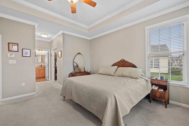 The convenient first floor master bedroom done in neutral tones is highlighted by the tray ceiling and crown molding. | Image 15