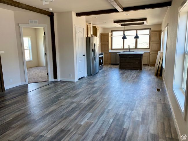 Kitchen featuring stainless steel fridge, beamed ceiling, dark wood-style floors, light countertops, and range | Image 8