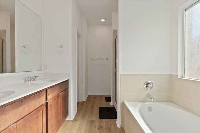 Full bathroom featuring a sink, a shower stall, a garden tub, double vanity, and wood finished floors | Image 8