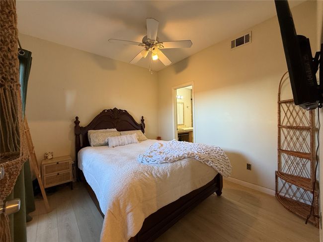 Bedroom with visible vents, light wood-style flooring, ensuite bathroom, ceiling fan, and baseboards | Image 13