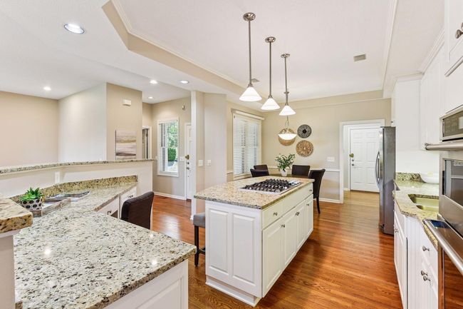 Chef's dream kitchen featuring stainless steel appliances, pendant lighting, and elegant granite surfaces throughout. | Image 12
