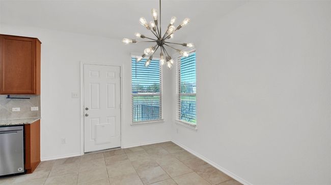 Unfurnished dining area with a chandelier, light tile patterned floors, and baseboards | Image 13