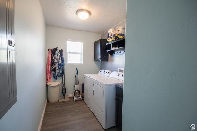 Clothes washing area with a textured ceiling, baseboards, independent washer and dryer, cabinet space, and dark wood-type flooring | Image 10