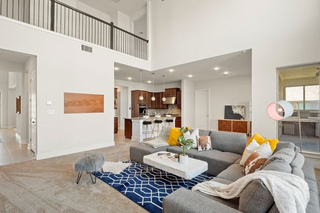 Living room featuring a high ceiling, light colored carpet, baseboards, visible vents, and recessed lighting | Image 8