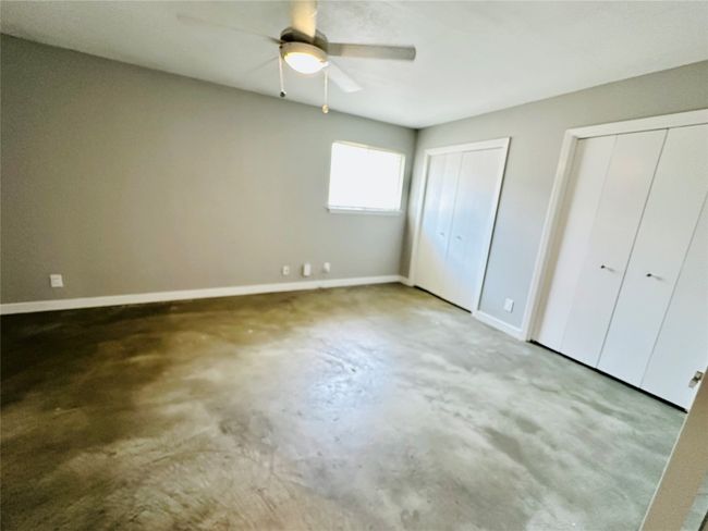 Unfurnished bedroom featuring concrete flooring, two closets, and ceiling fan | Image 12