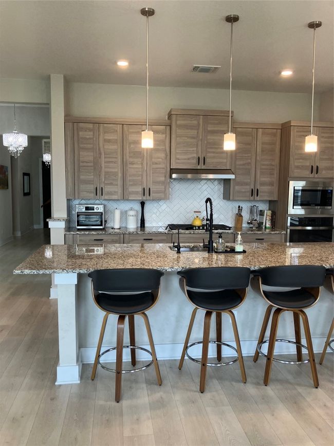 Kitchen with oven, a breakfast bar, backsplash, and light wood-style floors | Image 6