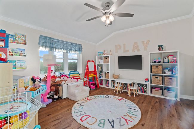 Game room with lofted ceiling, ornamental molding, wood finished floors, and a ceiling fan | Image 8