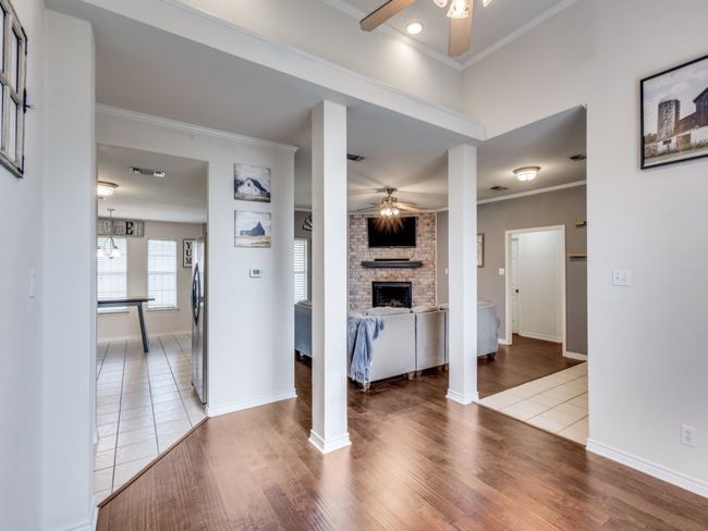 Unfurnished living room featuring a ceiling fan, ornamental molding, a fireplace, and wood finished floors | Image 6