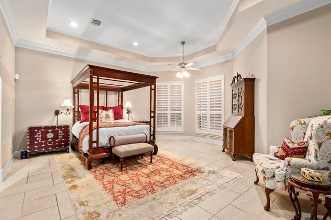 A serene space to begin each day, the primary bedroom suite boasts a stunning view of the natural landscape through the shuttered windows. This expansive retreat is secluded to its own wing of the house, ensuring privacy for homeowners as well as guests. | Image 17