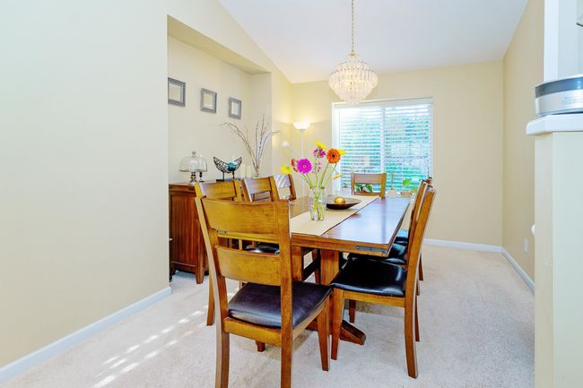 Dining area featuring a chandelier, light colored carpet, baseboards, and lofted ceiling | Image 5