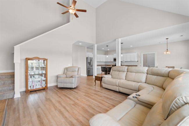 Living room featuring ceiling fan, light wood finished floors, high vaulted ceiling, stairway, and recessed lighting | Image 7