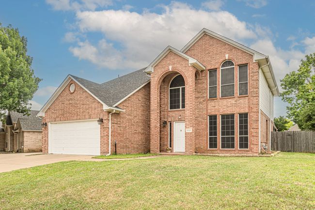 Traditional-style house featuring an attached garage, driveway, brick siding, and roof with shingles | Image 38